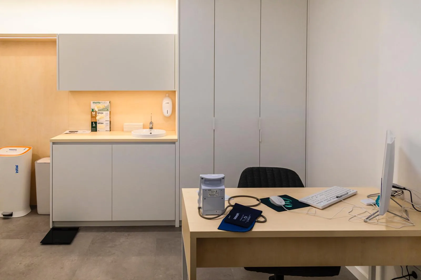 Consultório da Clínica Almada Care, com secretária, computador e equipamento médico.